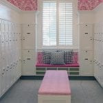 White wood lockers and bench with pink cushion in the middle by window at Quail Ridge Country Club Women's room.