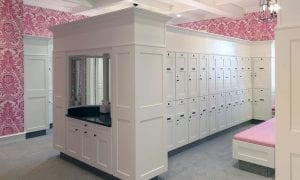 Quail Ridge Country Club locker room featuring white wood lockers and grooming station contrasting pink pattern on walls.