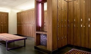 Laminate lockers, bench, and matching grooming station with pink light at Equinox Fitness.