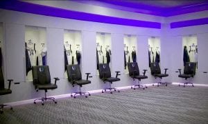 Dallas Mavericks locker room, white nanolam and solid surface lockers with branded black chairs in front.