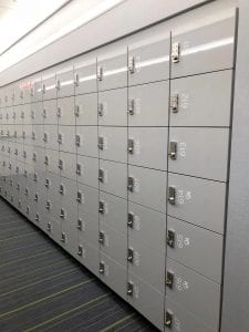 Row of high gloss laminate lockers with keyless 1 locks and white numbers on doors, viewed from right.