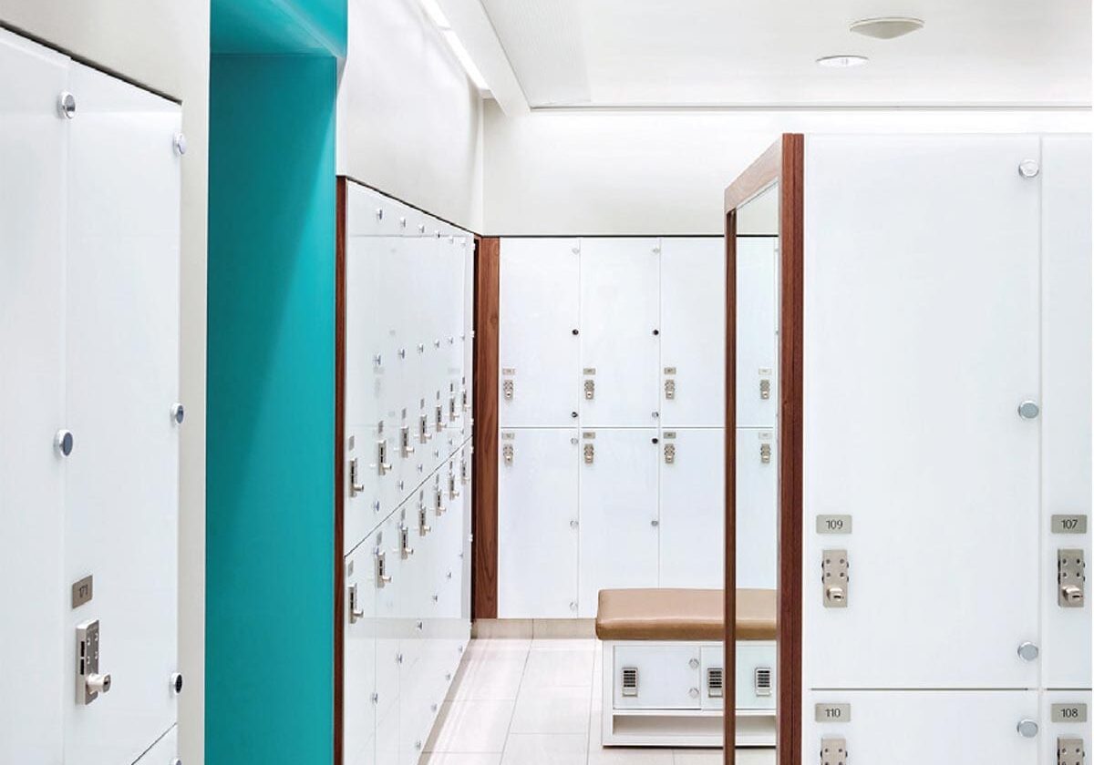 Locker room, white glass lockers and textured laminate edges on walls, in bench, and in high partition bisecting room.