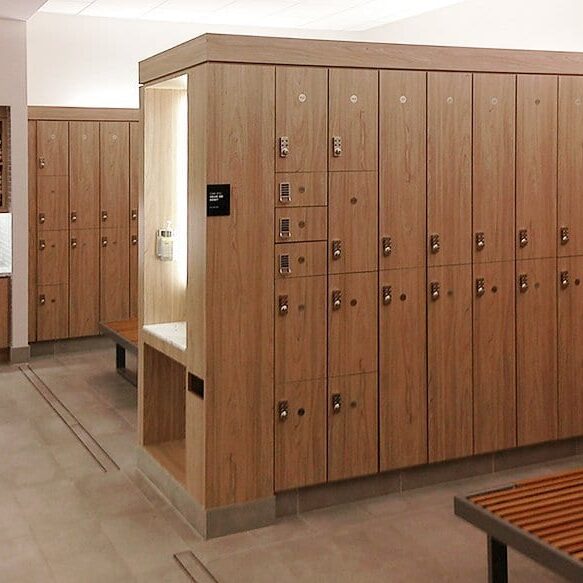 Equinox locker room with bays of laminate lockers, benches, grooming station and towel drops.